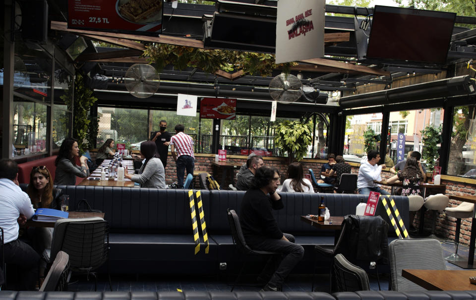 People sit in a re-opened cafe in Ankara, Turkey, Tuesday, June 1, 2021. Cafes and restaurants have re-opened in Turkey after President Recep Tayyip Erdogan's announcement Monday. Most of these establishments have stayed closed down for over a month and a half and Tuesday is their first day back at work.(AP Photo/Burhan Ozbilici)