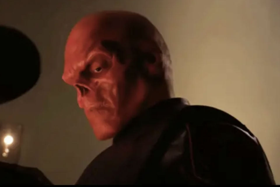 Red Skull from the Marvel Cinematic Universe, dressed in his dark menacing attire, glares intently. This character is significant in the Avengers movies