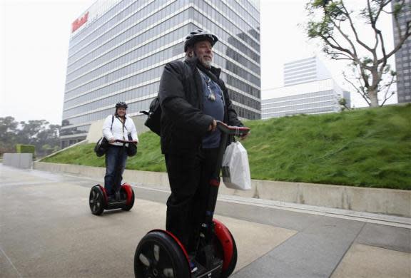 Apple co-founder Steve Wozniak carries the new iPad which he just purchased, as he and his wife Janet (L) ride their personal Segways to their hotel, after waiting in line overnight with customers to purchase the new iPad at the Apple Store in Century City Westfield Shopping Mall, Los Angeles, California March 16, 2012.