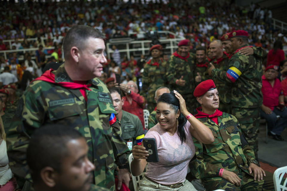 En esta imagen del 6 de febrero de 2019, la esposa de un soldado que fue parte de un grupo que atacó el palacio presidencial durante un fallido golpe militar en 1992 organizado por el difunto Hugo Chávez, revisa su peinado minutos antes del inicio del programa semanal de televisión "Con el Mazo Dando", dentro de una academia de aviación de Maracay, Venezuela. Para los simpatizantes del gobierno que asisten al programa perciben al anfitrión del show, Diosdado Cabello _ a quien Estados Unidos y la Unión Europea han sancionado por violaciones a los derechos humanos y corrupción _ con una idolatría similar a la que generó Elvis Presely. (AP Foto/Rodrigo Abd)