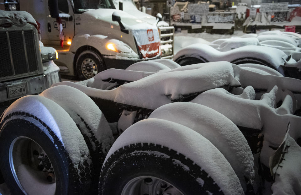 Snow covers the fifth wheel plates of semi-trailer trucks as a winter storm warning is in effect during a protest against COVID-19 measures in Ottawa, on Friday, Feb. 18, 2022. (Justin Tang /The Canadian Press via AP)