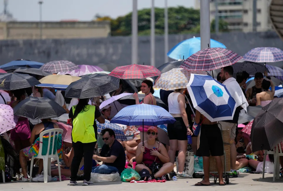 Taylor Swift fans wait for the doors of Nilton Santos Olympic stadium to open for her Eras Tour concert amid a heat wave in Rio de Janeiro, Brazil, Saturday, Nov. 18, 2023. A 23-year-old Taylor Swift fan died at the singer's Eras Tour concert in Rio de Janeiro Friday night, according to a statement from the show's organizers in Brazil. (AP Photo/Silvia Izquierdo)