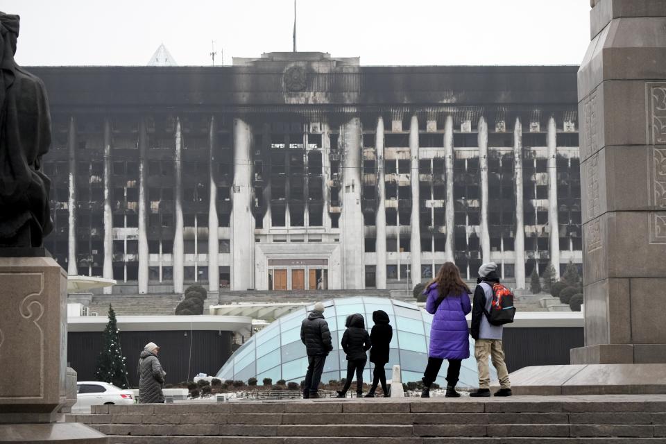 FILE - People look at the city hall building in the central square blocked by Kazakhstan troops and police in Almaty, Kazakhstan, Tuesday, Jan. 11, 2022. The country's political landscape changed markedly after a wave of violence in January 2022 when provincial protests initially sparked by a fuel price hike engulfed other cities, notably the commercial capital, Almaty, and became overtly political as demonstrators shouted "Old man out!" in reference to Nazarbayev. More than 220 people, mostly protesters, died as police harshly put down the unrest. ((AP Photo/Sergei Grits, File)