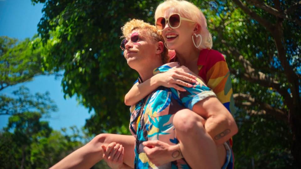 Wilder gives Corey a piggyback ride in a still from ‘Couple to Throuple’