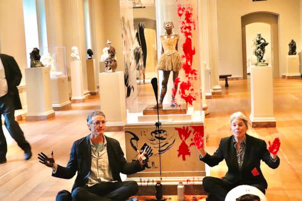 PHOTO: Declare Emergency protesters sit on the floor after smearing paint on the case and pedestal of Edgar Degas's 'Little Dancer Aged Fourteen' sculpture in the National Gallery of Art in Washington, Apr, 27, 2023. (AFP via Getty Images)