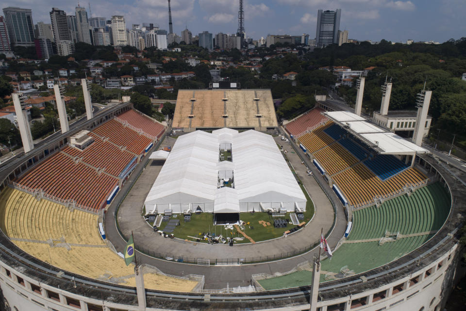 Workers set up a temporary field hospital to treat patients who have COVID-19 inside Pacaembu stadium in Sao Paulo, Brazil, Monday, March 30, 2020. The new coronavirus causes mild or moderate symptoms for most people, but for some, especially older adults and people with existing health problems, it can cause more severe illness or death.(AP Photo/Andre Penner)