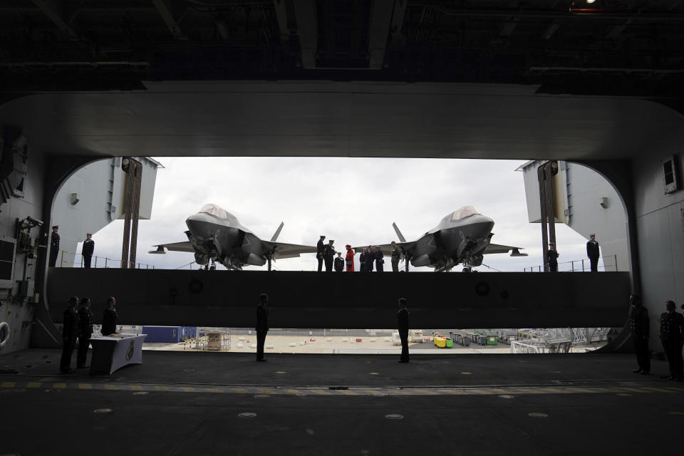 Britain's Queen Elizabeth II , centre, on the flight deck, with a pair of F-35B Lightning II aircraft on either side, during a visit to HMS Queen Elizabeth at HM Naval Base, ahead of the ship's maiden deployment, in Portsmouth, England, Saturday May 22, 2021. HMS Queen Elizabeth will be leading a 28-week deployment to the Far East that Prime Minister Boris Johnson has insisted is not confrontational towards China. (Steve Parsons/Pool Photo via AP)