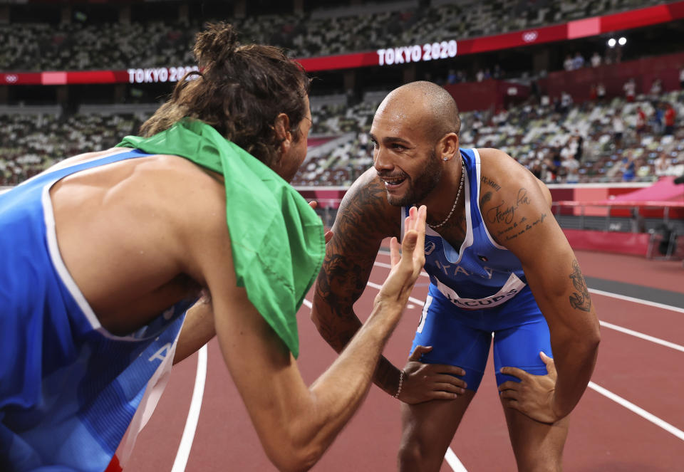 Lamont Marcell Jacobs of Italy is congratulated by teammate Gianmarco Tamberi after winning the final of the men's 100-meters at the 2020 Summer Olympics, Sunday, Aug. 1, 2021 in Tokyo, Japan. (Cameron Spencer/Pool Photo via AP)