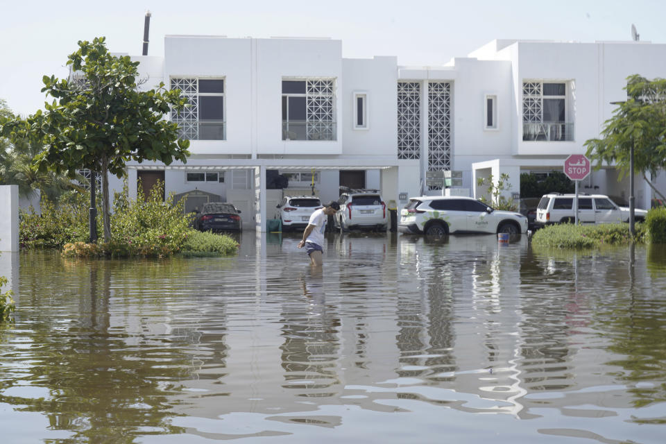 A man walks through floodwater in the Mudon neighborhood in Dubai, United Arab Emirates, Thursday, April 18, 2024. The United Arab Emirates attempted to dry out Thursday from the heaviest rain the desert nation has ever recorded — a deluge that flooded out Dubai International Airport and disrupted flights through the world's busiest airfield for international travel. (AP Photo/Jon Gambrell)