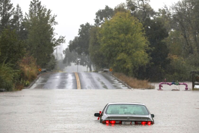 A vehicle sits in flood waters near the Russian River off River and Slusser roads in Forestville, Calif. on Sunday, Oct. 24