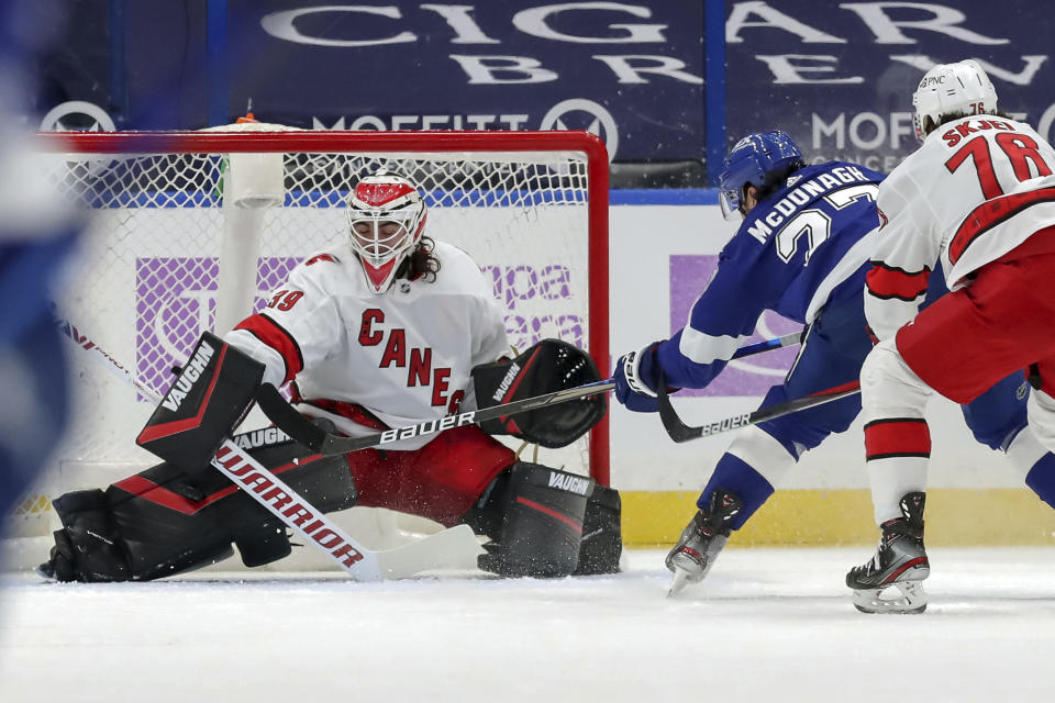 Carolina Hurricanes goaltender Alex Nedeljkovic makes a pad save on a shot from Tampa Bay Lightning's Ryan McDonagh as Steven Lorentz (78) defends during the first period of an NHL hockey game Tuesday, April 20, 2021, in Tampa, Fla. (AP Photo/Mike Carlson)