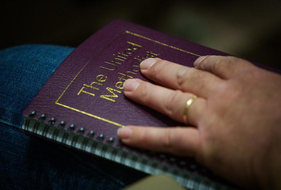 A man holds a book Friday, May 6, 2022, as delegates and others visit inside Kingsway Christian Church on Friday, May 6, 2022, to attend the Global Legislative Assembly of the Wesleyan Covenant Association being held in Avon, Ind. 