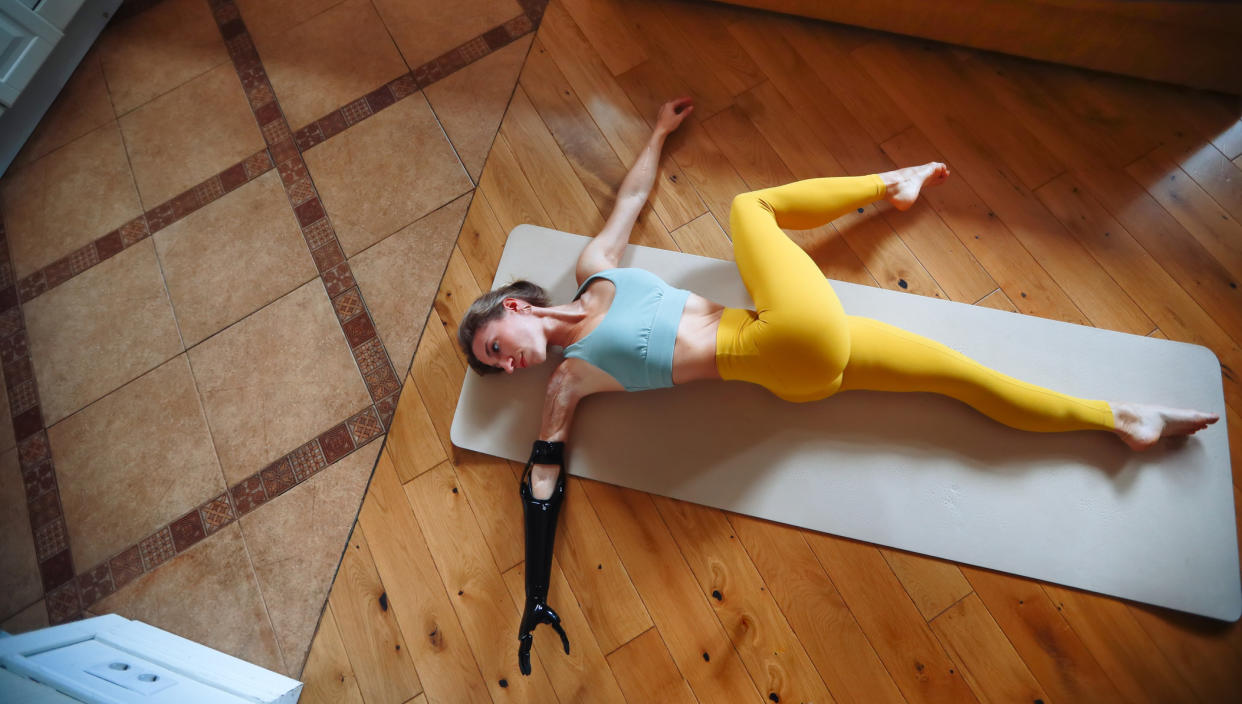  Woman lying on floor performing back twist. 