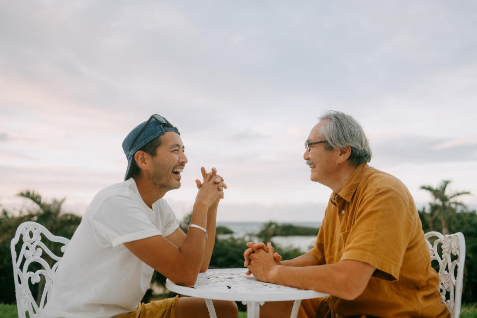 Two people smiling and enjoying a conversation at a table outdoors