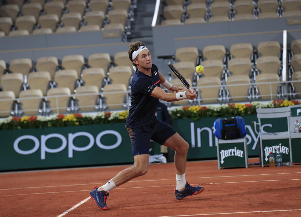 Empty seats from the background as Norway's Casper Ruud plays a shot against Austria's Dominic Thiem in the third round match of the French Open tennis tournament at the Roland Garros stadium in Paris, France, Friday, Oct. 2, 2020. (AP Photo/Michel Euler)