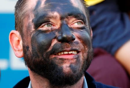 A spectator with his face painted in black watches the parade of "The Savage" during the festival Ducasse d'Ath in Ath