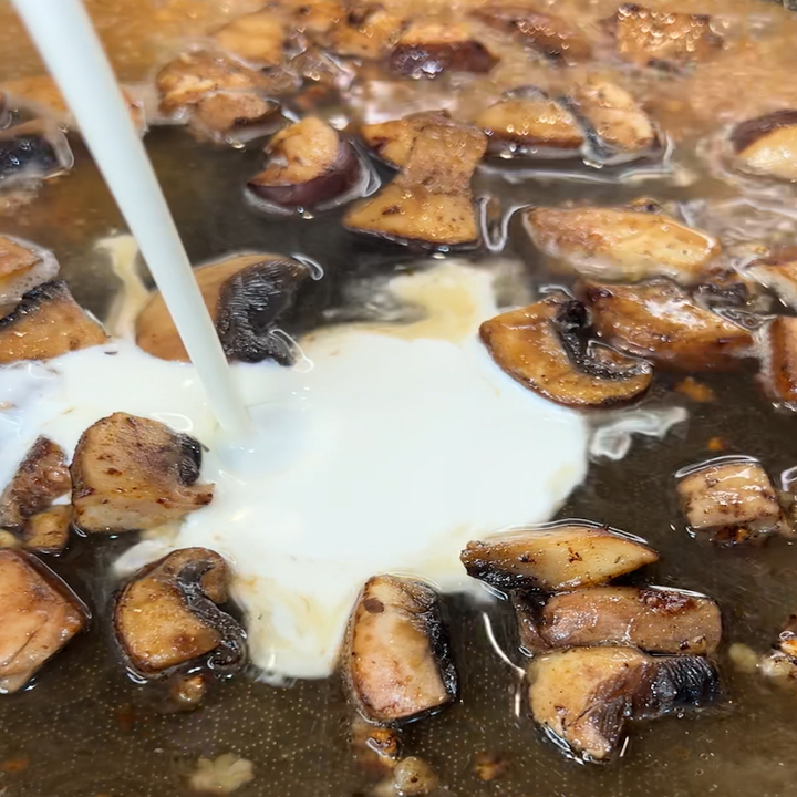 Heavy whipping cream being added to the pan