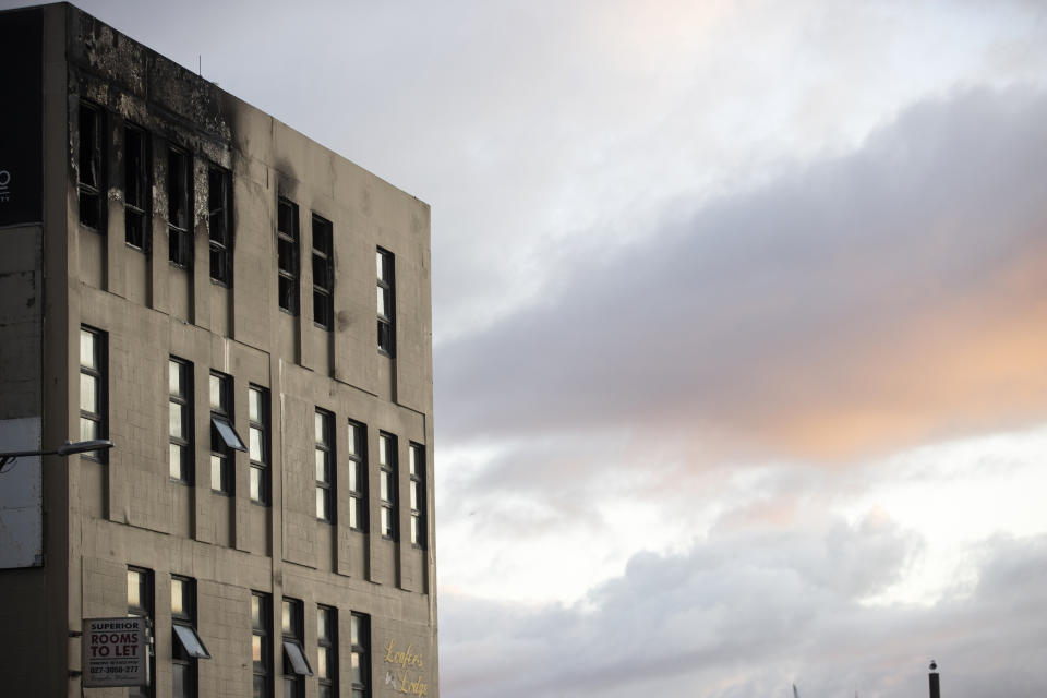 Morning light bathes the scene Wednesday, May 17, 2023, after an apartment fire at Loafers Lodge in Wellington, New Zealand. A fire ripped through the hostel in New Zealand's capital Tuesday, killing multiple people and forcing others to flee the four-story building in their pajamas in what a fire chief called his "worst nightmare." (George Heard/New Zealand Herald via AP)