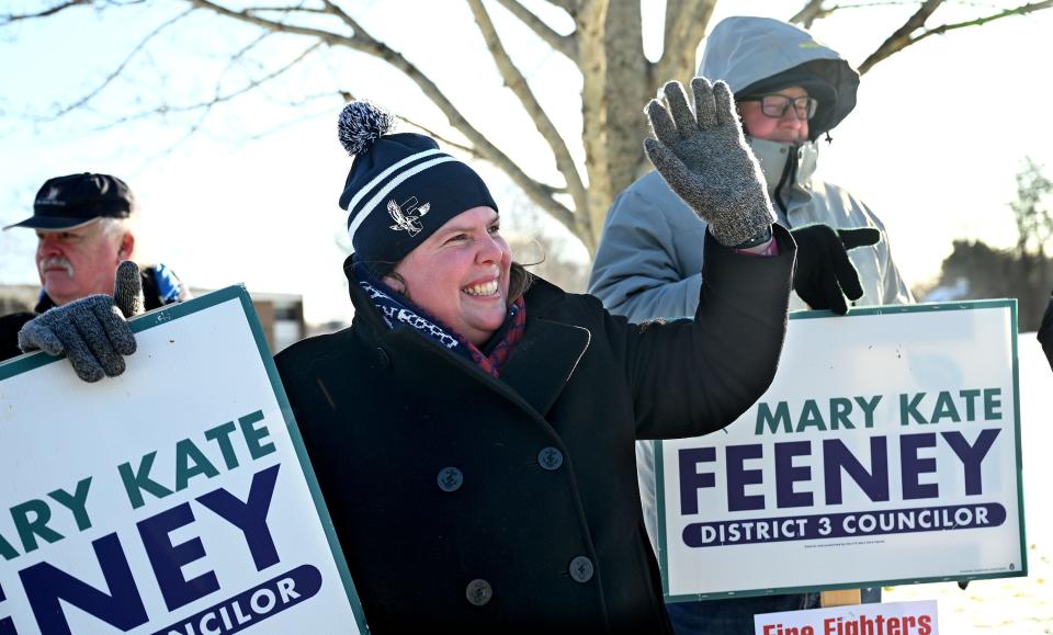 Mary Kate Feeney waves to voters while holding a sign in the bitter cold outside the Brophy Elementary School during a special election in the District 3 City Council race, Jan. 11, 2021.