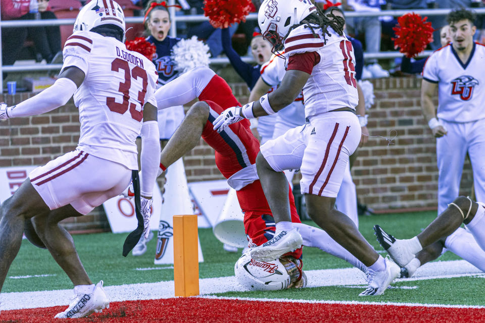 FILE - Liberty's Kaidon Salter, center, is upended short of the goal line against Massachusetts' Darius Gooden, Derrieon, Craig and Jerrod Cameron during the second half of an NCAA college football game, Nov. 18, 2023, in Lynchburg, Va. The Mid-American Conference is inviting UMass to join as a full member, starting in 2025, a person familiar with the decision told The Associated Press on Monday, Feb. 26, 2024. (AP Photo/Robert Simmons, File)