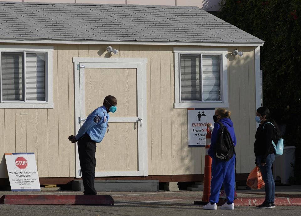 A hospital security guard keeps his social distance as people inquire about COVID-19 tests outside the CHA Hollywood Presbyterian Medical Center (CHA HPMC) in Los Angeles Tuesday, Jan. 5, 2021. Los Angeles is the epicenter of California's surge that is expected to get worse in coming weeks when another spike is expected after people traveled or gathered for Christmas and New Year's. Much of the state is under a stay-home order and open businesses are operating with limited capacity. (AP Photo/Damian Dovarganes)