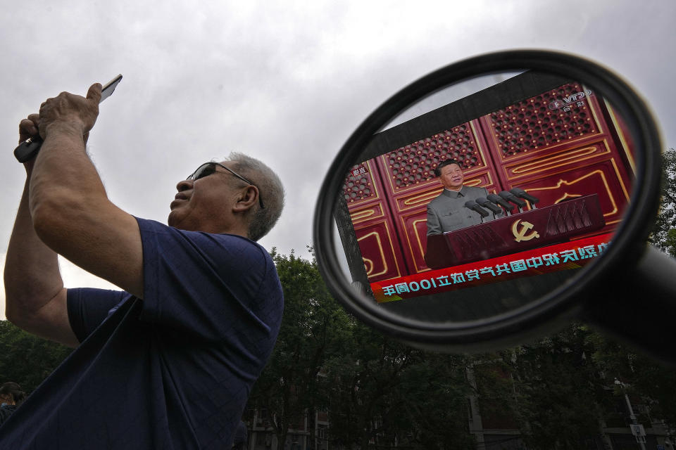 A man uses his smartphone to film a large video screen showing Chinese President Xi Jinping speaking during an event to commemorate the 100th anniversary of China's Communist Party at Tiananmen Square, outside a shopping mall in Beijing, Thursday, July 1, 2021. China's ruling Communist Party is marking the 100th anniversary of its founding with speeches and grand displays intended to showcase economic progress and social stability to justify its iron grip on political power. (AP Photo/Andy Wong)