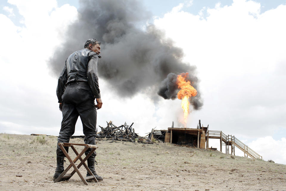 man standing in the desert as a building explodes