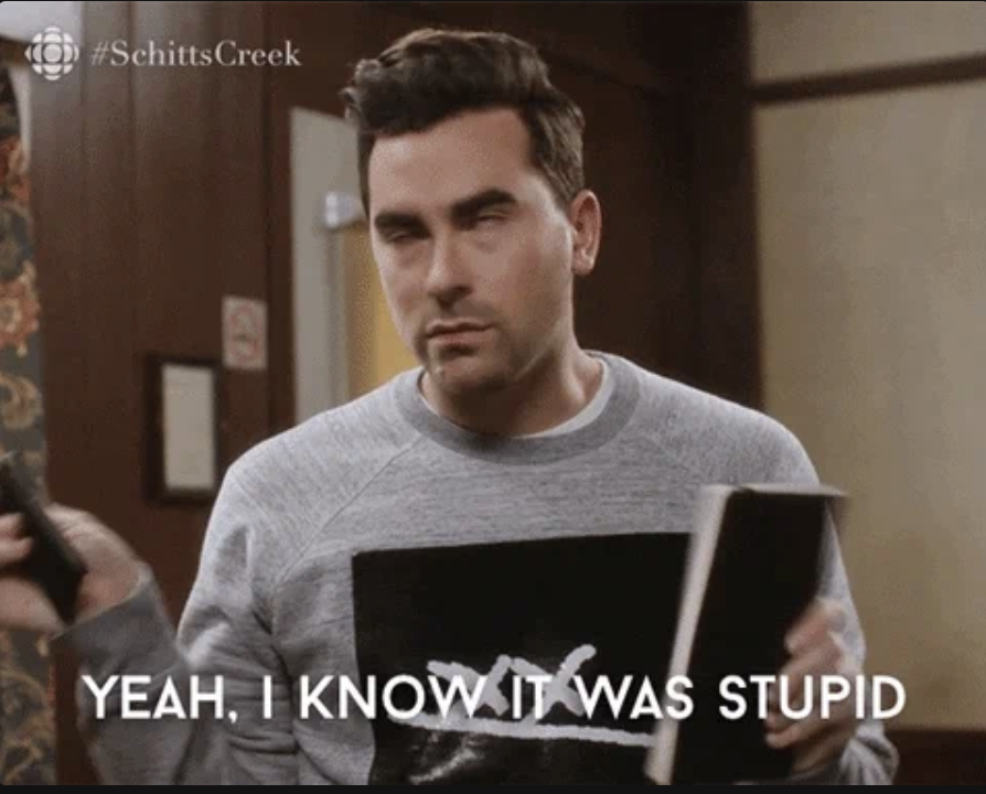 Dan Levy from Schitt's Creek, holding a book and shaking his head, with the caption, "YEAH, I KNOW IT WAS STUPID."