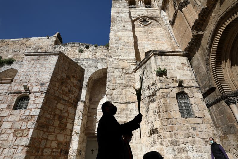 An Orthodox Christian worshipper is silhouetted as he holds a palm frond outside the closed doors of the Church of the Holy Sepulchre on Orthodox Palm Sunday amid the coronavirus disease (COVID-19) outbreak, in Jerusalem's Old City