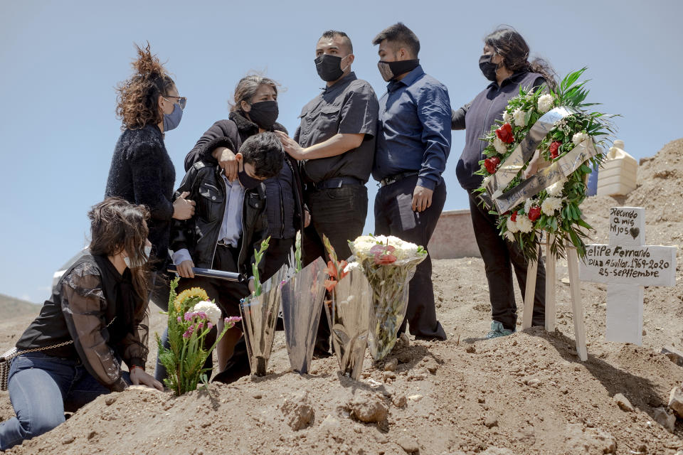 A family wearing protective masks mourns during the burial of a relative who died from coronavirus at Municipal Cemetery No. 13 in Tijuana, Mexico, on May 12. | Fred Ramos—Bloomberg/Getty Images