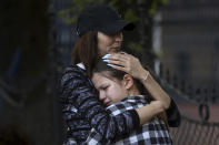 A woman hugs a girl near the Vladislav Ribnikar school in Belgrade, Serbia, Wednesday, May 3, 2023. A 13-year-old who opened fire Wednesday at his school in Serbia's capital drew sketches of classrooms and made a list of people he intended to target in a meticulously planned attack, police said. He killed eight fellow students and a guard before calling the police and being arrested. (AP Photo/Armin Durgut)