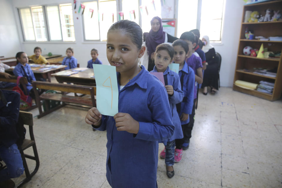 FILE - In this July 20, 2017 file photo, Syrian refugee children between the ages of six and 12 line up in a first-grade classroom for a lesson in summer school in Amman, Jordan. When Jordan’s main border crossing with Syria reopened in October 2018, after four years, there were hopes that refugees would begin to return home, but few are taking up the offer. Many Jordanian schools now operate in double shifts to accommodate refugee children. (AP Photo/Reem Saad, File)