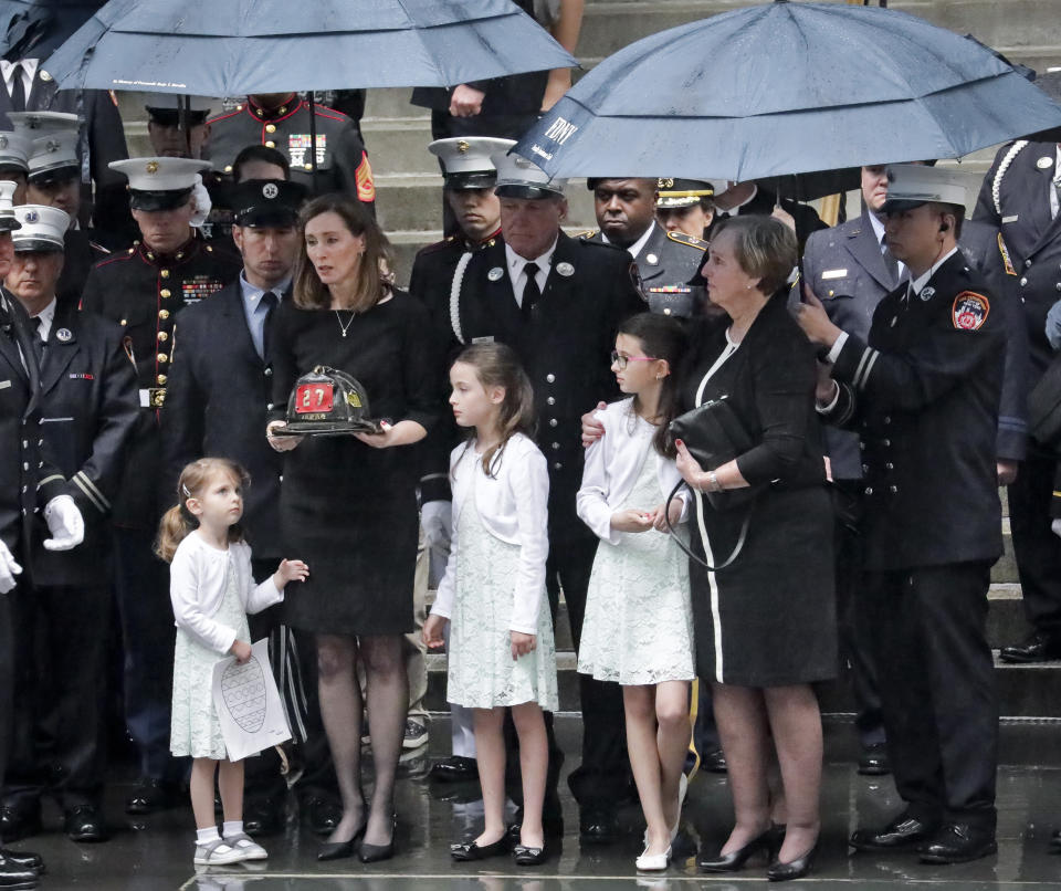 Shannon Slutman holds the fire helmet her late husband, U.S. Marine Corps Staff Sergeant and FDNY Firefighter Christopher Slutman, as his casket leaves St. Thomas Episcopal Church, Friday April 26, 2019, in New York. (AP Photo/Bebeto Matthews)