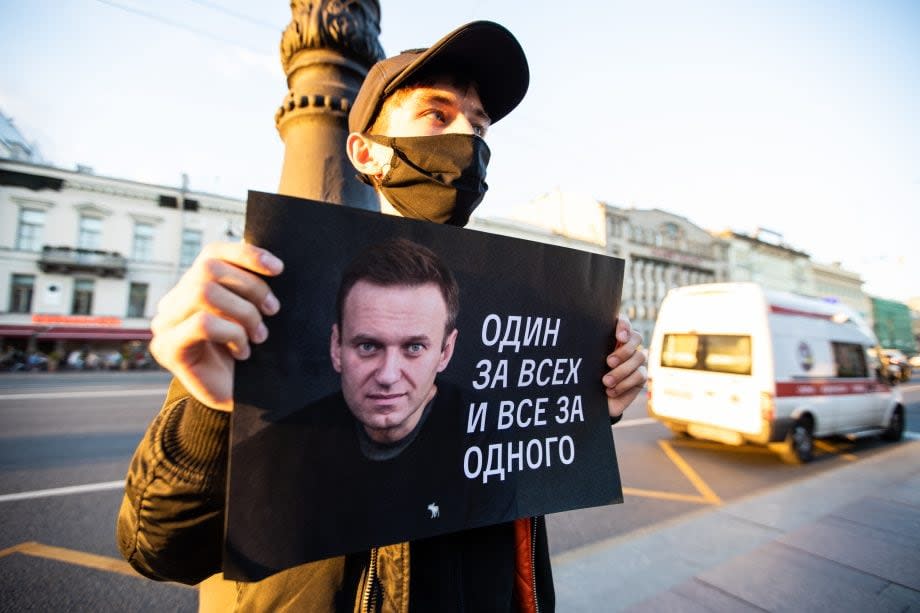 Nawalny-Protestant hält ein Protestschild hoch auf dem Nawalnys Gesicht zu sehen ist. Daneben steht der Spruch: 