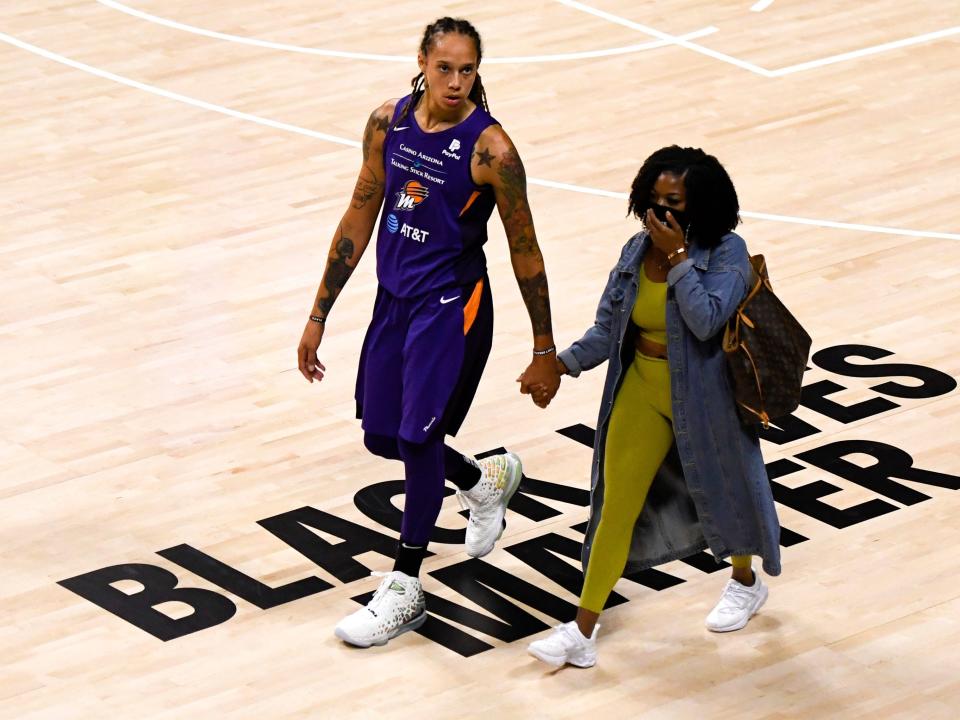 Brittney and Cherelle Griner hold hands as they walk across a Basketball court.