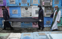 FILE - Catholic priest Rev. Flaviano "Flavie" Villanueva walks with funeral workers in protective suits as they carry the remains of a victim of an alleged extrajudicial killing at a public cemetery in Manila, Philippines on Sept. 17, 2021, after it was exhumed due to an expired contract to rent the grave. An International Criminal Court chief prosecutor, Karim Khan, said on June 24, 2022 that he has sought authorization from the court to resume an investigation into drug killings as a possible crime against humanity, from Nov. 1, 2011 when outgoing Philippine President Rodrigo Duterte was still a Davao mayor to March 16, 2019. (AP Photo/Aaron Favila, File)