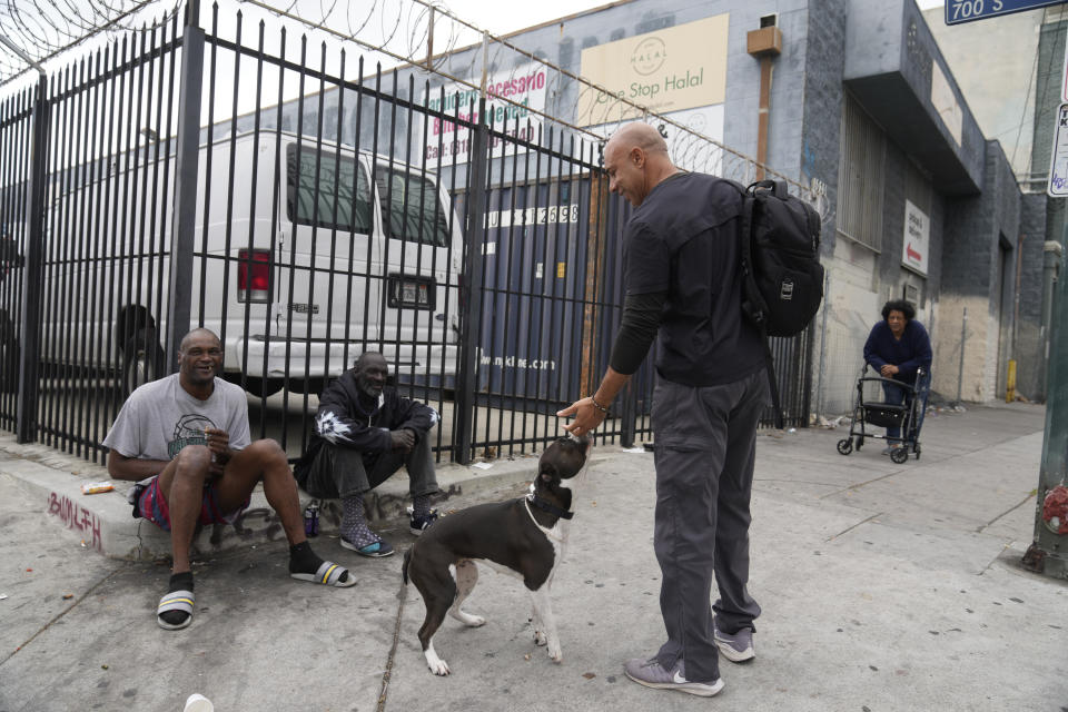 Dr. Kwane Stewart asks people for the owner of a dog in the Skid Row area of Los Angeles on Wednesday, June 7, 2023. Stewart, 52, is a lifelong animal lover who grew up in Texas and New Mexico trying to save strays — or at least care for them any way he could. (AP Photo/Damian Dovarganes)