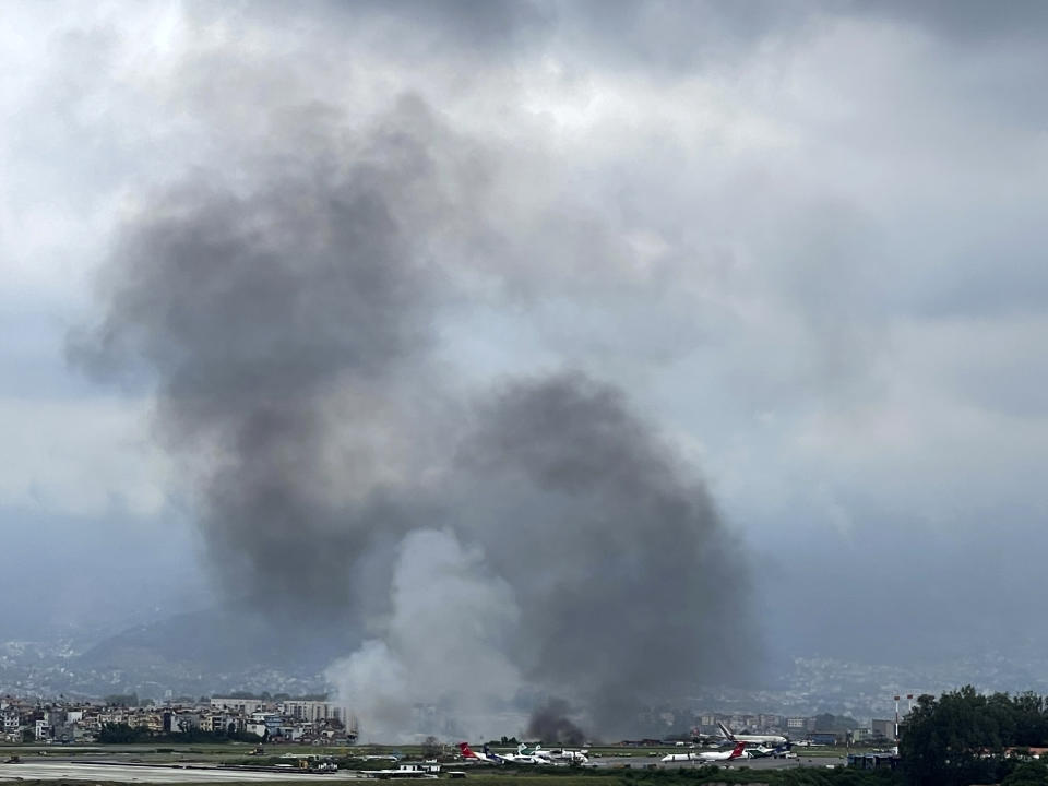 Una columna de humo sale del Aeropuerto Internacional Tribhuvan, en Katmandú, Nepal, el 24 de julio de 2024. Según la televisora estatal nepalí, un avión se salió de la pista y se estrelló cuando intentaba despegar del aeropuerto de Katmandú. (AP Foto/Agniia Galdanova)