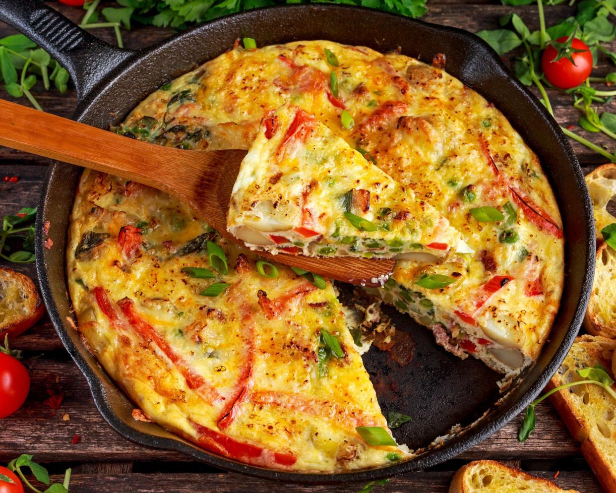 frittata in metal skillet, wooden spoon