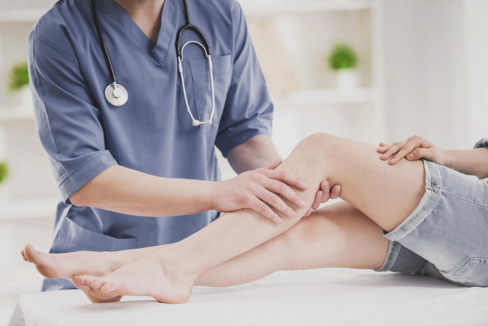 A doctor touches a patient's leg as they lay on an examination table