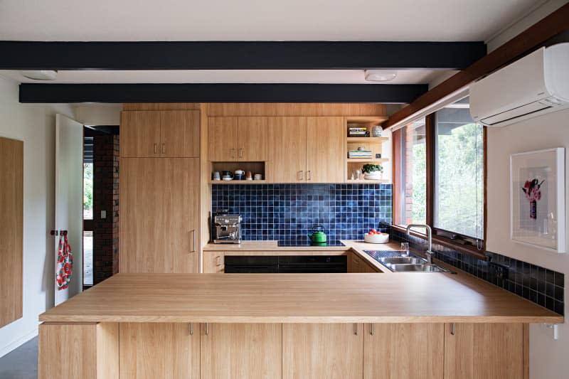 view into kitchen. Lots of wood cabinets, shelves, counters, blue tile backsplash