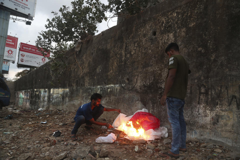 Izhaar Hussain Shaikh, left, an ambulance driver who works for HelpNow, an initiative to help the stretched services of first responders, burns his protective suit, after dropping a COVID-19 patient at a hospital in Mumbai, India May 28, 2020. It’s an exhausting job and Shaikh's daily shifts are grueling, sometimes even stretching to 16 hours. For a city that has a history of shortage of ambulances and where coronavirus pandemic has claimed hundreds of lives, putting the health care system under immense strain, every help counts. (AP Photo/Rafiq Maqbool)