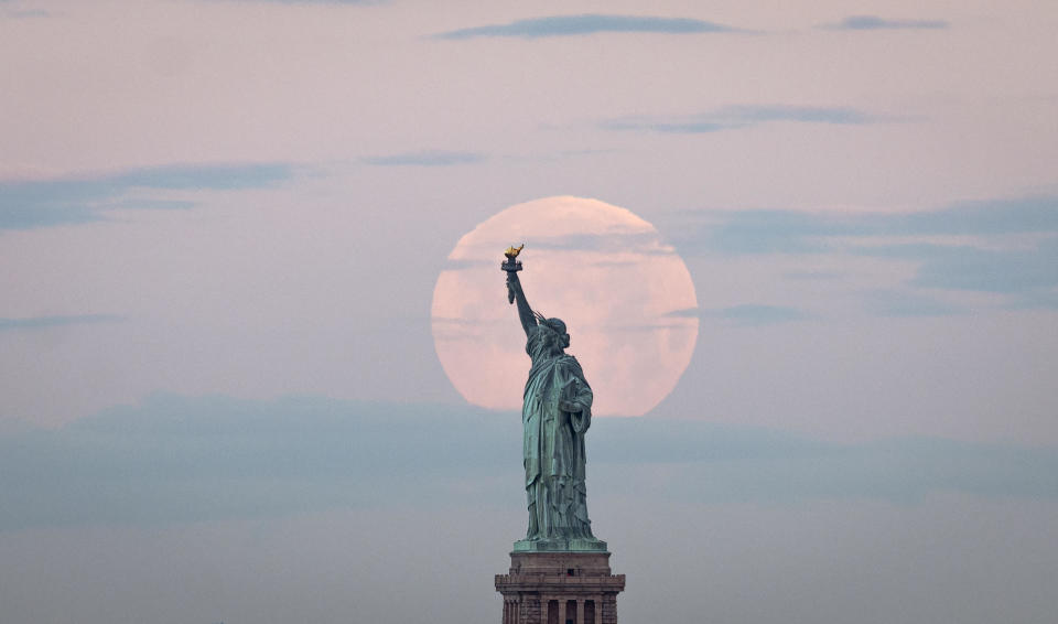 May's full Moon, known as the Full Flower Moon, the last supermoon of the year, sets behind the Statue of Liberty on May 7, 2020 in New York City. / Credit: JOHANNES EISELE/AFP via Getty Images