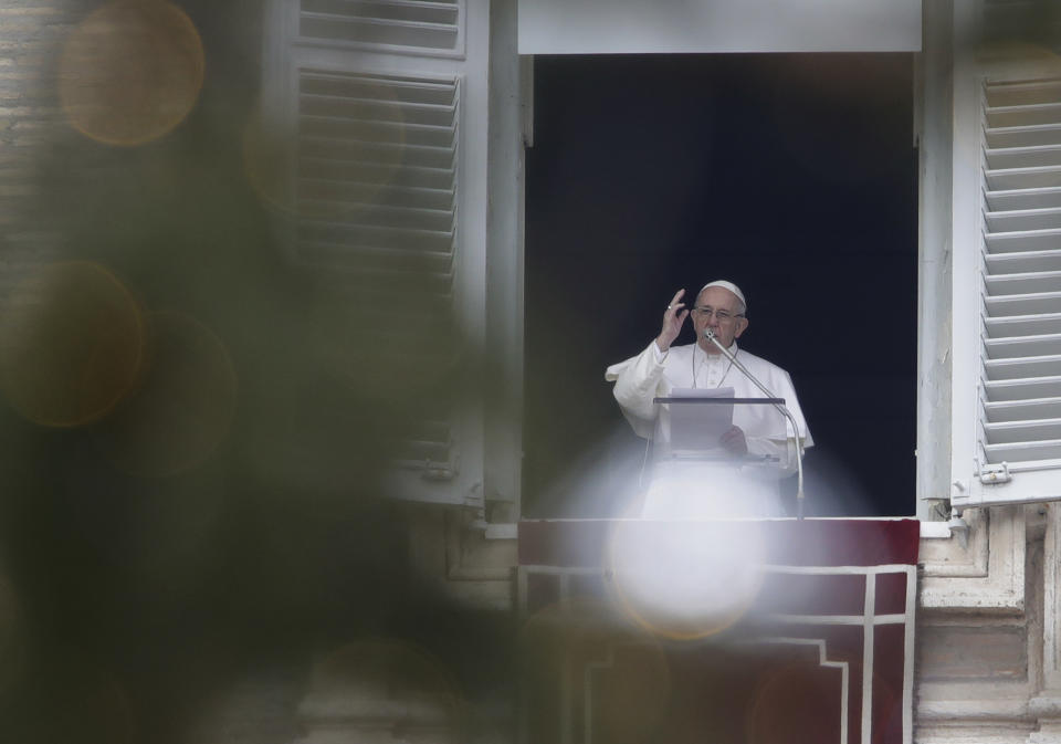Framed by a Christmas tree, Pope Francis blesses the crowd as he recites the Angelus noon prayer from the window of his studio overlooking St.Peter's Square, at the Vatican, Sunday, Jan. 13, 2019. (AP Photo/Alessandra Tarantino)