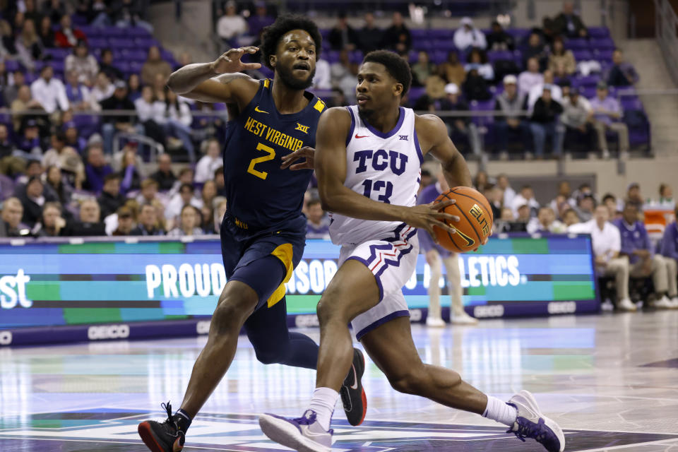 West Virginia's Kobe Johnson (2) defends against a drive to the basket by TCU guard Shahada Wells (13) in the first half of an NCAA college basketball game, Tuesday, Jan. 31, 2023, in Fort Worth, Texas. (AP Photo/Ron Jenkins)