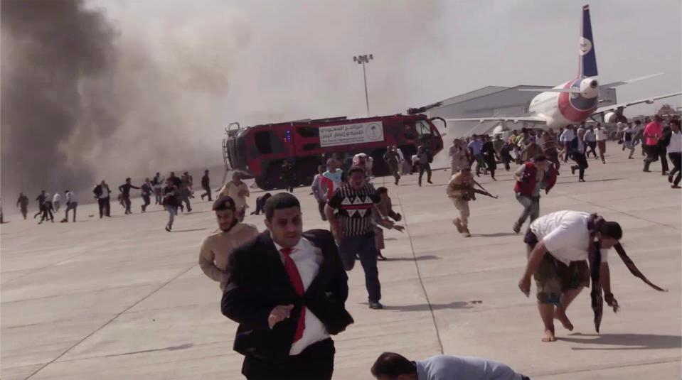 <p>People run following an explosion at the airport in Aden on Wednesday 30 December</p> (AP)