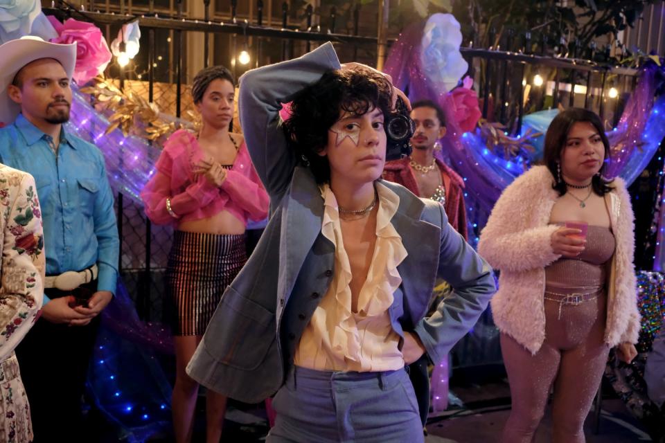 Actor Roberta Colindrez is shown in a blue suit in a party setting on the set of the TV show "Vida"