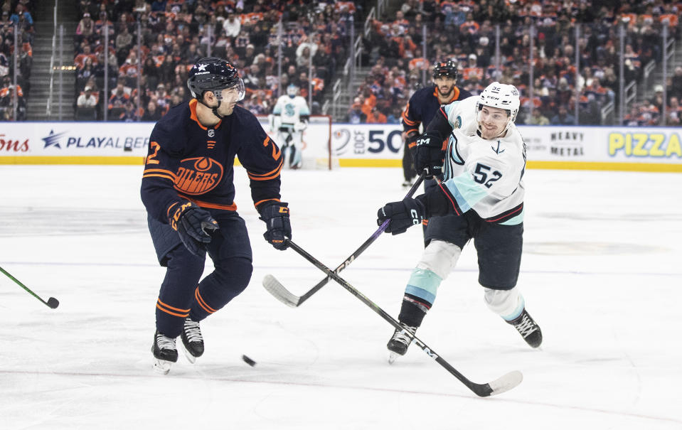 Seattle Kraken's Tye Kartye (52) shoots as it goes off Edmonton Oilers' Evan Bouchard (2) during first-period NHL hockey game action in Edmonton, Alberta, Thursday, Jan. 18, 2024. (Jason Franson/The Canadian Press via AP)