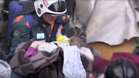 A still image taken from a video footage showsaA rescuer carries a 11-month-old child found alive in the rubble of a Russian apartment block that partially collapsed after a suspected gas blast in Magnitogorsk, Russia January 1, 2019. Minister of Civil Defence, Emergencies and Disaster Relief/Handout via REUTERS TV