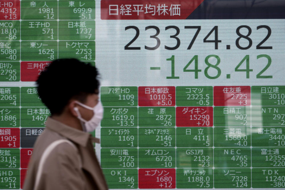 A man walks past an electronic stock board showing Japan's Nikkei 225 index at a securities firm in Tokyo Tuesday, Feb. 18, 2020. Shares have fallen in Asia as the impact from the virus outbreak that began in China deepened, with Apple saying it would fail to meet its profit target and China moving to cancel major events including the Beijing auto show. (AP Photo/Eugene Hoshiko)